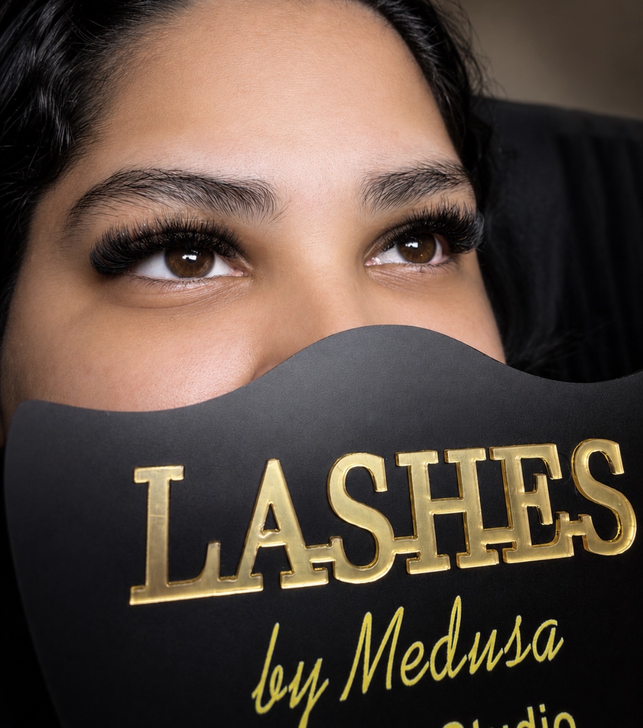 Client showing a Lashes by Medusa sign after her appointment